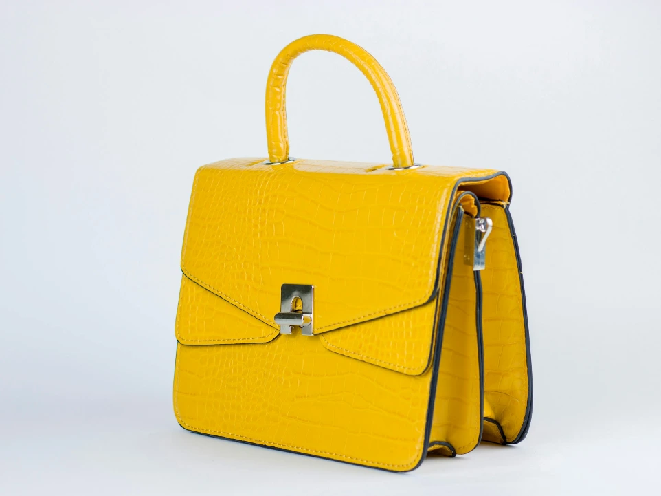a yellow handbag with a handle on a white background